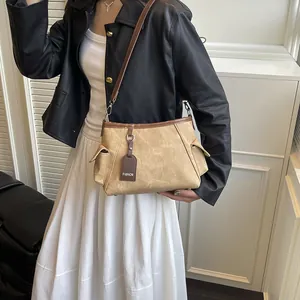 Chic khaki and brown contrast bucket bag worn by model with black leather jacket