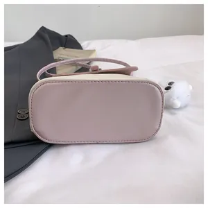 Detail view of pink and beige mini crossbody bag bottom with fine stitching craft