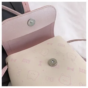 Detail of pink cartoon cat print small crossbody bag with circular magnetic metal clasp