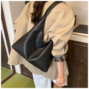 Detailed close-up of a black woven leather tote bag shown on a female model's shoulder