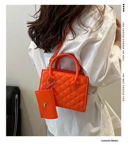 Sac à main matelassé orange avec pochette assortie porté à l'épaule en situation réelle