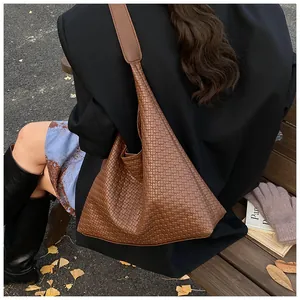 Detailed view of dark brown woven tote bag with Intrecciato texture and wide shoulder strap