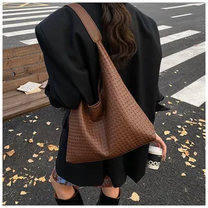 Detail of dark brown woven leather hobo tote bag with wide strap in an autumn street setting