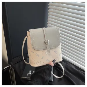 Detail of printed crossbody bag featuring silver heart buckle and cute cat pattern