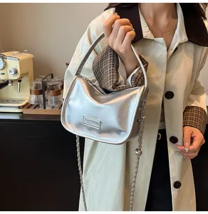 Silver glossy patent leather square bag with chain strap shown in a lifestyle street setting
