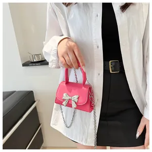 Fashionable rose pink mini crossbody bag with a large silver bow and chain strap