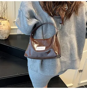 Detail of glossy brown faux leather handbag with silver hardware and brand label