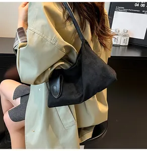 Detail view of black canvas and leather trapezoid shoulder bag with side buckle accent