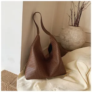 Detail view of a woven leather hobo tote in caramel finish within a minimalist setting