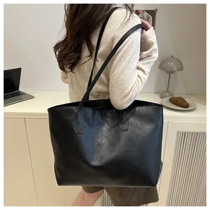 Side view of large black leather tote bag with lychee texture and thin shoulder straps