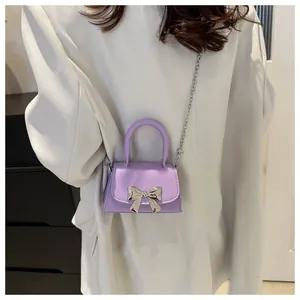 Chic light purple mini crossbody bag with silver bow detail worn with a white blazer