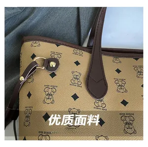 Close-up of textured tote bag leather with bear pattern and gold metal hardware