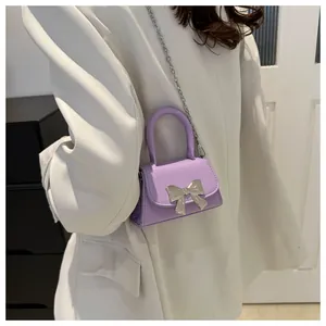Detail of lavender mini square bag with silver metal bow worn with a white blazer