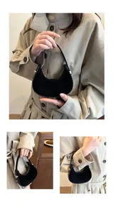 Detail view of mini black suede crescent handbag with gold hardware and metal zipper