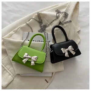 Close-up of mini flap bags in green and black with a metallic silver bow buckle