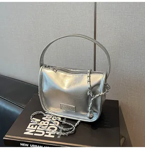 Detail of silver metallic textured handbag with Fashion logo and silver chain strap