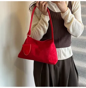 Macro detail of red faux suede underarm bag with a decorative side knot and charm