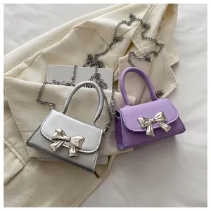 Detailed shot of mini chain bags with metallic bow and fine faux leather texture