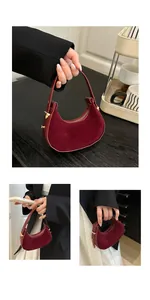 Detailed view of dark red suede half-moon handbag with gold hardware and zipper