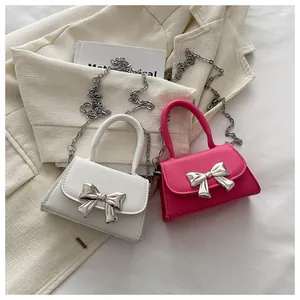Detail of mini leather bags with silver metallic bow and chain on a beige blazer