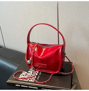 Detail of red patent leather handbag with chain strap and glossy finish on urban books