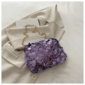 Detail der lila Pailletten-Umhängetasche mit Goldkette auf beigem Blazer