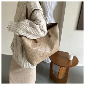 Detail view of woven leather tote bag texture with brown handles in cozy interior setting