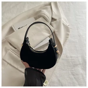 Detail of minimalist black crescent handbag with gold zipper and smooth matte texture