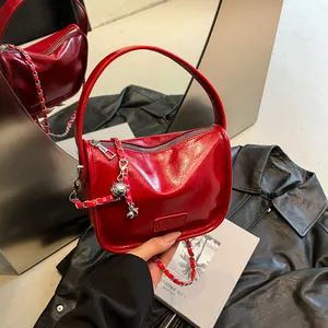 Glossy red patent leather crossbody bag with silver chain strap and metallic ball charm