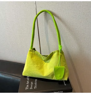 Détail du sac à main en daim vert avec anse en cuir sur fond de livre minimaliste