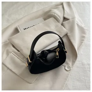 Detailed interior view of a black crescent suede bag holding lipstick and earbuds
