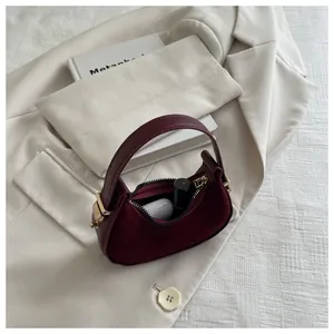 Detail of burgundy faux suede moon bag showing storage for lipstick and earbuds case