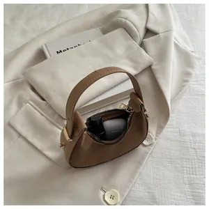 Detailed view of mini brown suede crescent bag with gold zipper and essentials inside