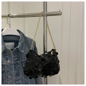 Detail einer schwarzen Paillettentasche mit goldener Kette auf Jeansjacke
