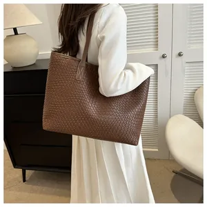 Detail of wide woven leather tote bag in dark brown with single shoulder strap