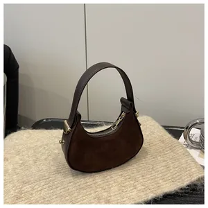 Detail of dark brown suede half-moon bag with gold hardware on a knit background