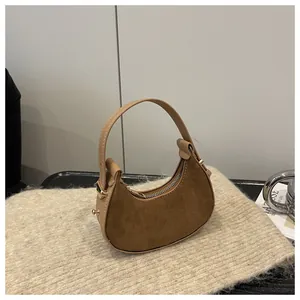 Detail of suede crescent bag showing smooth leather trim and premium gold hardware