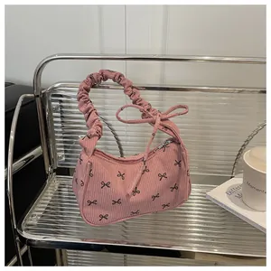 Pink corduroy bag with black bow prints and a ruffled cloud handle on a modern shelf