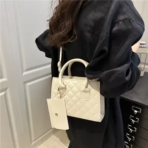 Sac bandoulière matelassé avec poignées et mini pochette porté par un mannequin