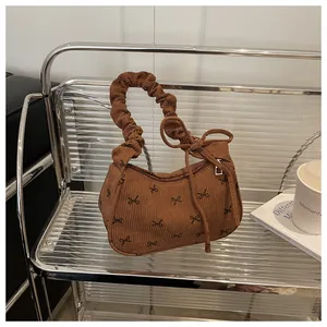 Detailed view of brown corduroy shoulder bag with bow pattern and scrunchie handle