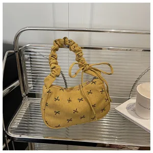Close-up of yellow corduroy underarm bag with black bow prints and scrunchie handle