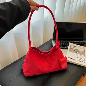 Sac hobo moderne en daim rouge avec mini porte-monnaie sur un fond de chaise design