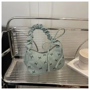 Detail of light green corduroy handbag with black bow patterns and ruffled handle