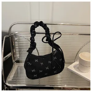 Detail of corduroy underarm bag with white bow prints and ruched handle on display shelf