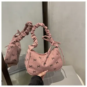 Detailed macro view of pink corduroy underarm bag featuring black bow patterns and ruffled handle