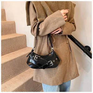 Dettaglio borsa a mezzaluna nera lucida con fibbie argentate indossata con cappotto