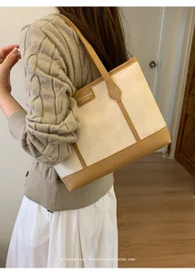 Close-up of a cream tote bag with brown leather trim and a minimalist brand tag