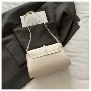Close-up of cream leather shoulder bag with fine stitching and magnetic buckle closure