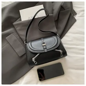 Detail of black matte leather shoulder bag featuring magnetic closure and diagonal zip pockets