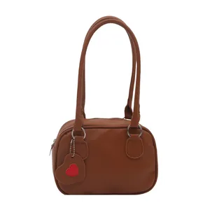 Dark brown pebble leather bowling bag with long handles and a heart charm accessory